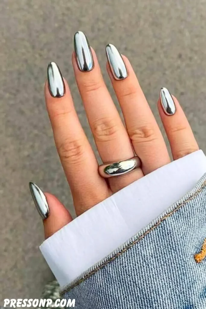 A close-up of a hand with long, square nails featuring a vibrant neon pink French manicure accented with futuristic metallic silver chrome abstract swirls and 3D stars.
