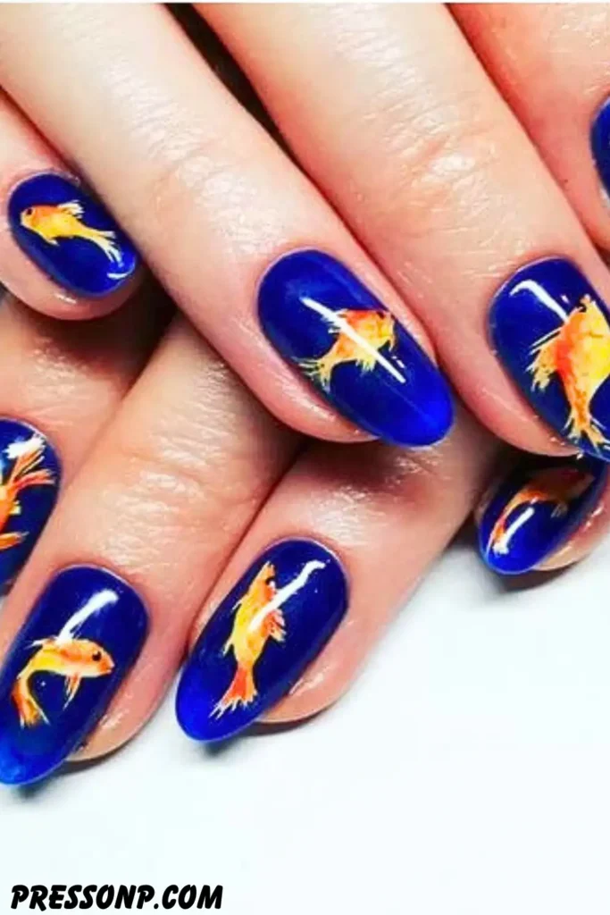 A close-up of short, rounded nails showcasing a dark navy blue magnetic cat-eye manicure decorated with small, vibrant hand-painted neon tropical fish.