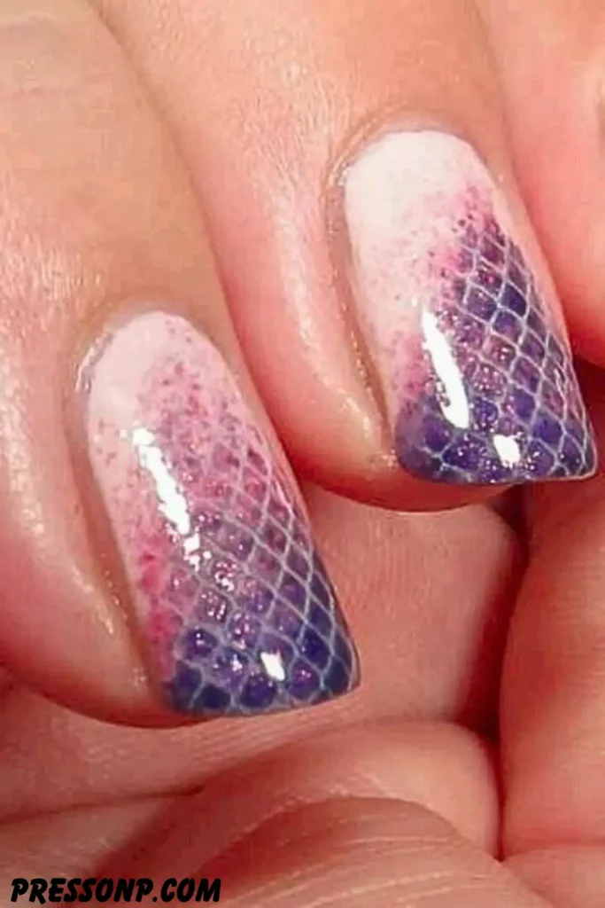A macro close-up of fingers featuring a textured fish scale manicure with a pink-to-purple gradient shimmer finish.