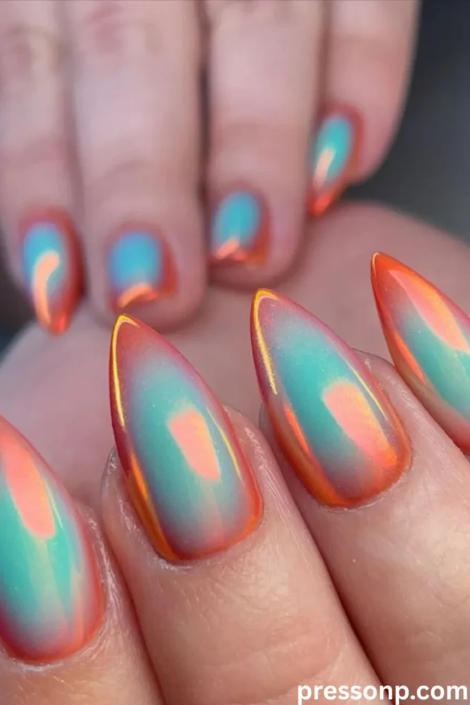 A close-up of sharp, stiletto-shaped extension nails featuring a vibrant aura design that shifts from a soft turquoise blue outer base to a glowing, blurred bright orange-coral center with an iridescent chrome glaze.