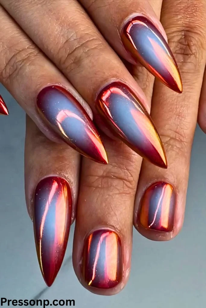 A close-up of a hand featuring a "cat eye" or magnetic manicure. The almond-shaped nails have a deep emerald green base with a shimmering silver diagonal streak that creates a futuristic, dimensional shine.