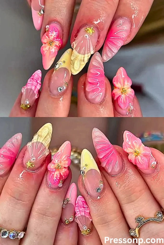 A close-up of hands featuring a vibrant 3D "mermaid-core" manicure. The almond-shaped nails are decorated with raised textures mimicking seashells and blooming flowers in bright pink and soft yellow tones.