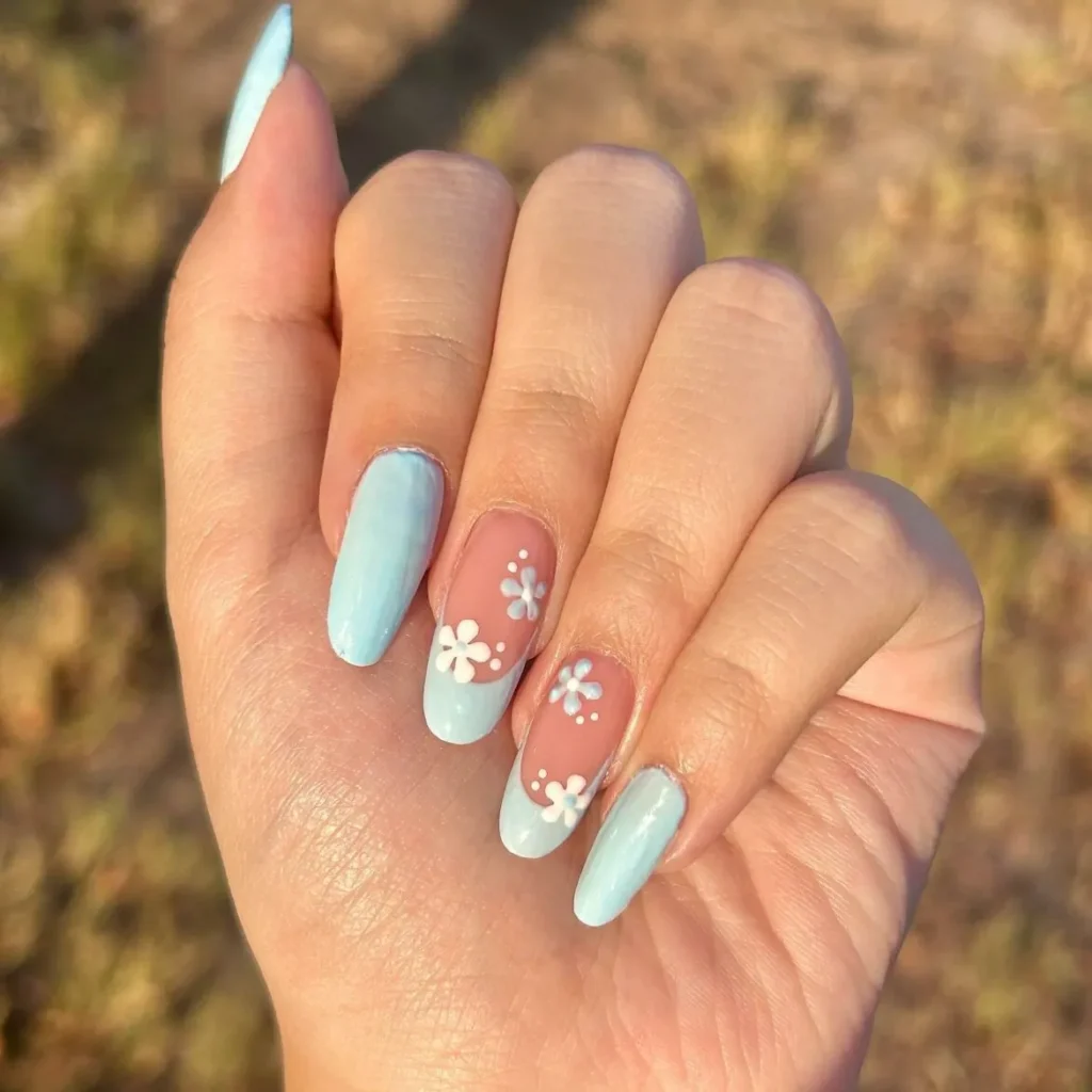 A close-up of long, almond-shaped nails featuring a solid, glossy pastel sky-blue color mixed with matching light blue French tips and delicate white daisy floral art.