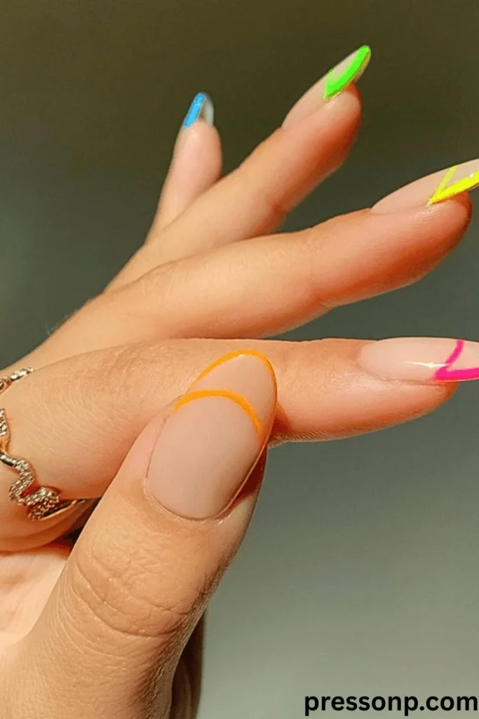 A close-up of a hand showcasing long, almond-shaped nails with a smooth matte nude base, featuring a vibrant rainbow of neon outline French tips and matching negative-space crescent accents on each finger.