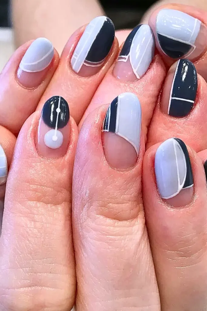 "Modern negative space nail art featuring a palette of cool grey, slate blue, and crisp white. The design uses geometric blocks and thin white lines over a clear base to create an optical illusion, showcasing a top 'eye-tricking' nail trend for Summer 2026."