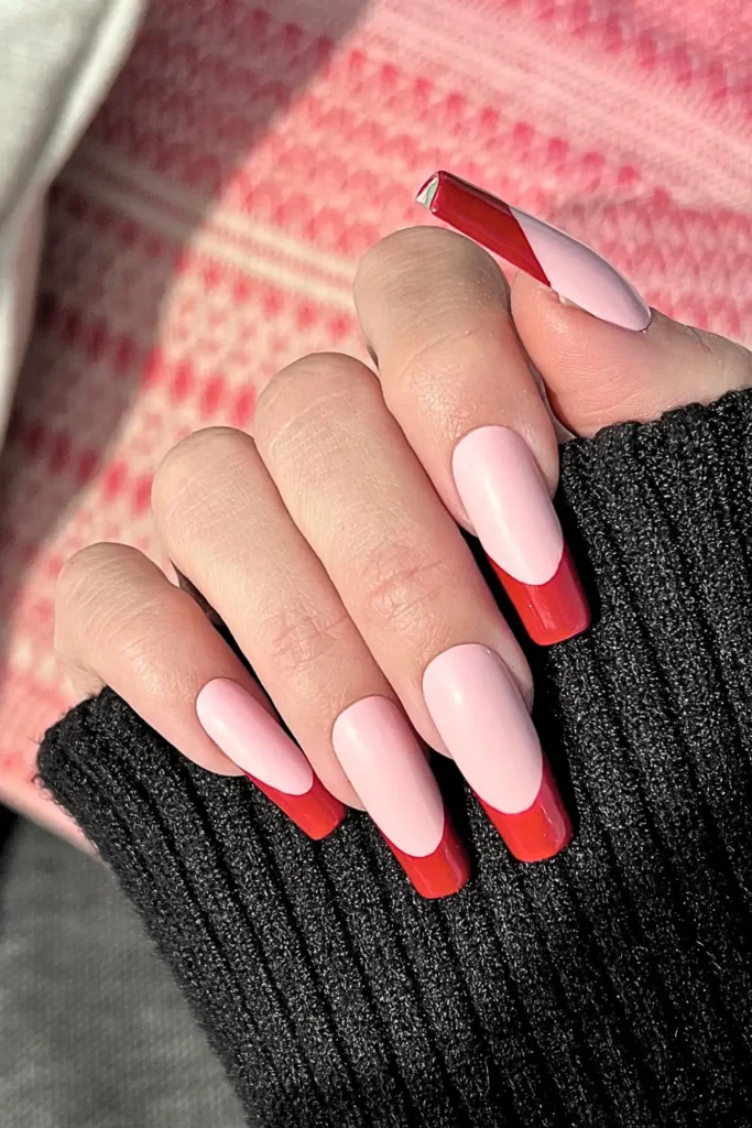 "Long, square-shaped nails featuring a modern twist on the French manicure. A soft baby pink base is paired with bold, deep red 'smile line' tips and a diagonal abstract geometric design on the thumb, showcasing the Summer 2026 minimalist nail art trend."