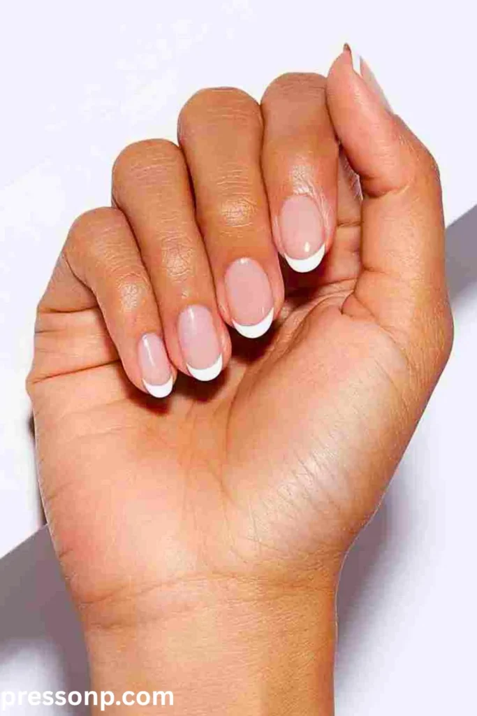 A close-up of long, natural almond-shaped nails featuring a clean nude base coat with an asymmetric, minimalist black line painted along just one side of each nail tip.