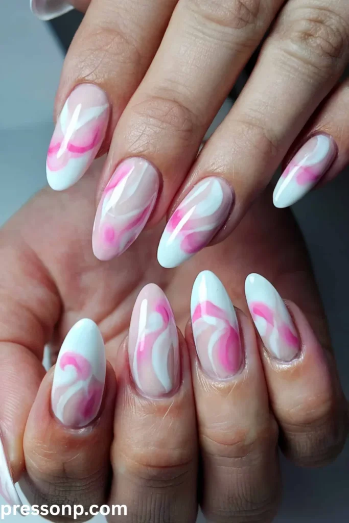 A close-up of almond-shaped nails featuring a translucent, sheer pink base decorated with abstract, fluid swirls of milky white and vibrant magenta pink