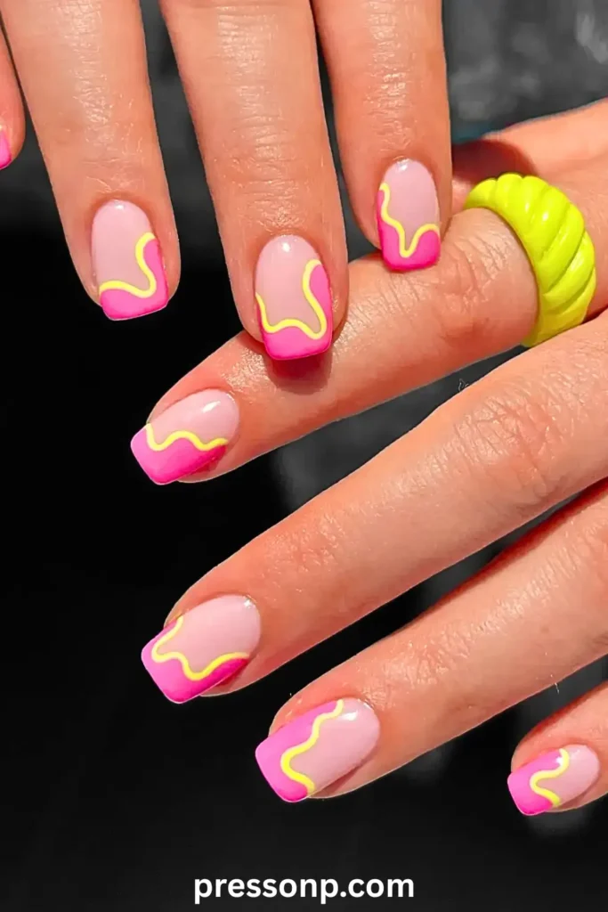 Short square nails with a natural base featuring neon pink French tips and a vibrant yellow squiggle line, accessorized with a chunky neon yellow ring.