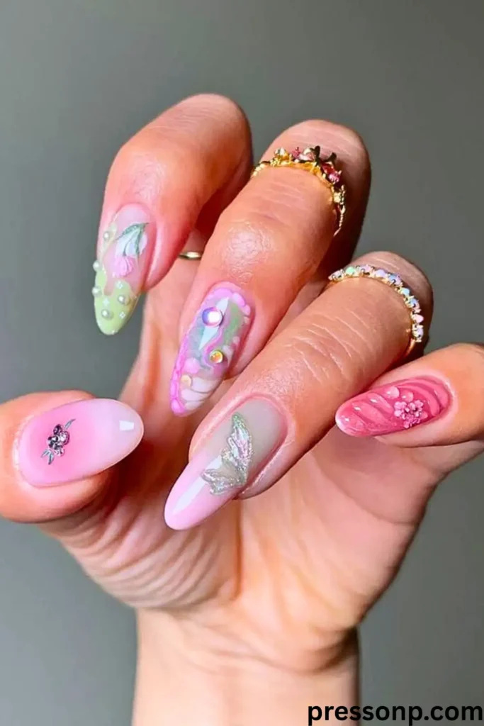 A hand featuring a "Happy & Whimsical" pastel rainbow manicure. Each almond-shaped nail is decorated with unique 3D textures, including iridescent butterfly wings, floral patterns, and delicate pearl accents.