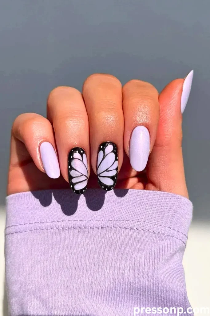 A close-up of a hand with almond-shaped nails featuring a "butterfly chrome" finish that shifts between iridescent purple, blue, and green hues.