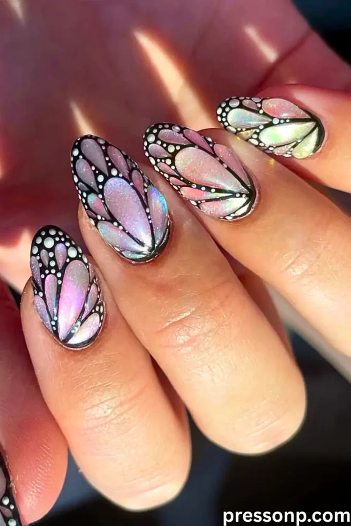 A close-up of almond-shaped nails featuring a "Glitter Butterfly Dust" design with iridescent shimmering wing segments outlined in bold black.