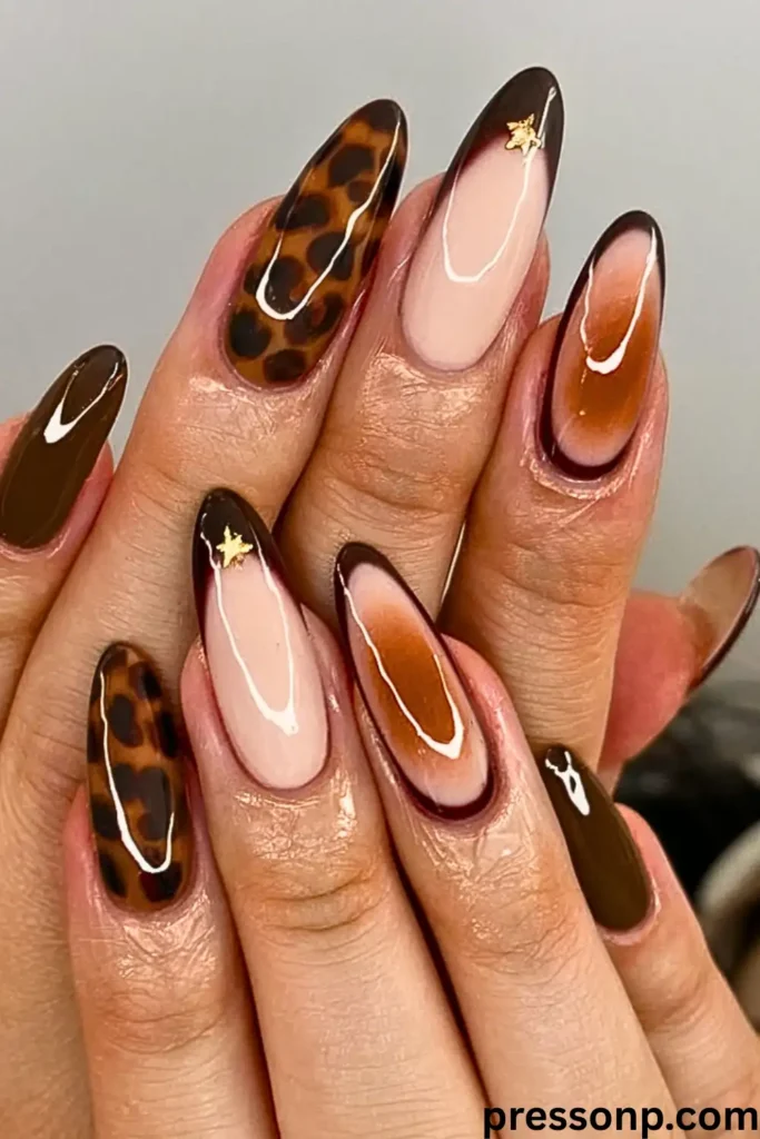 A close-up of a hand with long, almond-shaped nails featuring an "Unexpected & Earthy" manicure that mixes full tortoiseshell patterns, solid dark olive green, and tortoiseshell French tips accented with small gold stars.