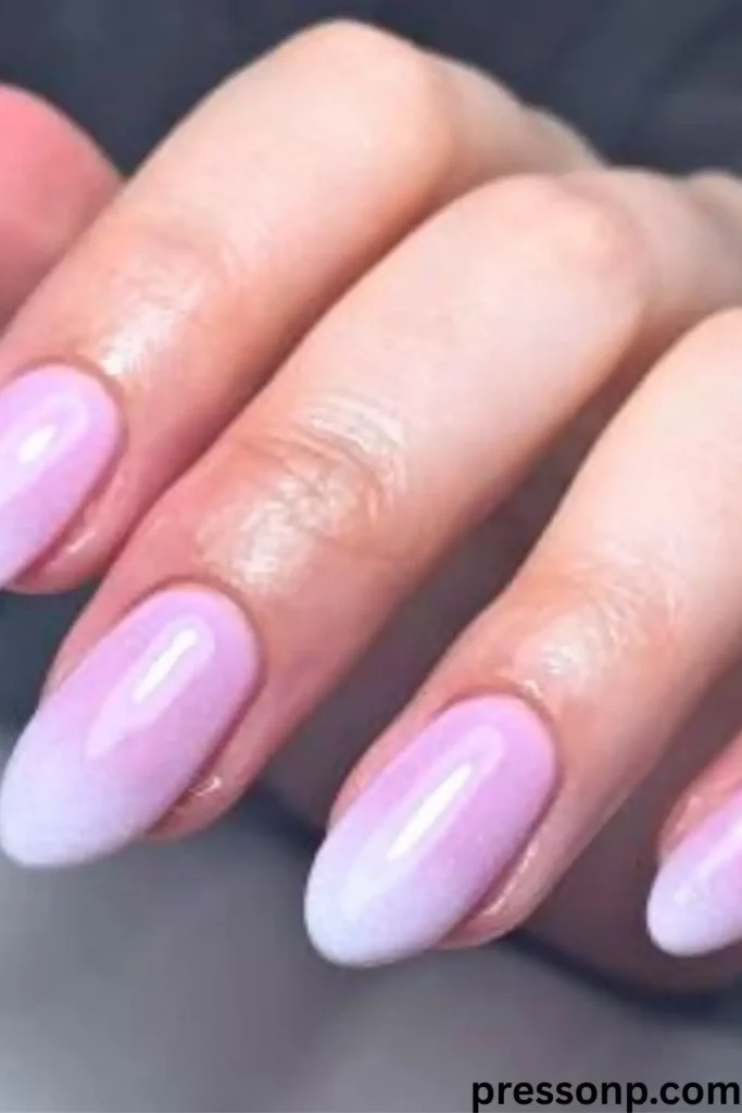 A close-up of long, oval-shaped nails showcasing a classic French ombré manicure with a soft, seamless gradient fading from a neutral nude base to soft white tips.