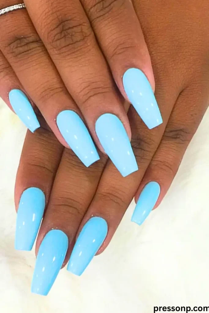 A close-up of hands displaying long, coffin-shaped "Ocean Blue Jelly Nails" finished with a sleek, high-gloss sky blue polish.