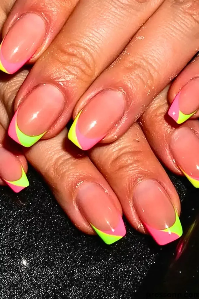 A close-up of a hand with medium square-shaped nails featuring a double-layer French manicure with overlapping neon pink and neon lime green tips.