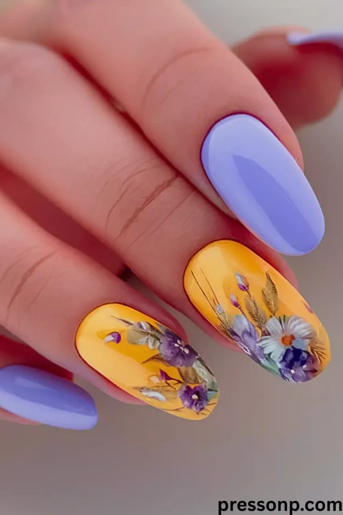 A close-up of a hand with long oval nails showcasing a mixed manicure of solid pastel lavender polish and vibrant yellow accent nails featuring detailed, hand-painted watercolor floral artwork.