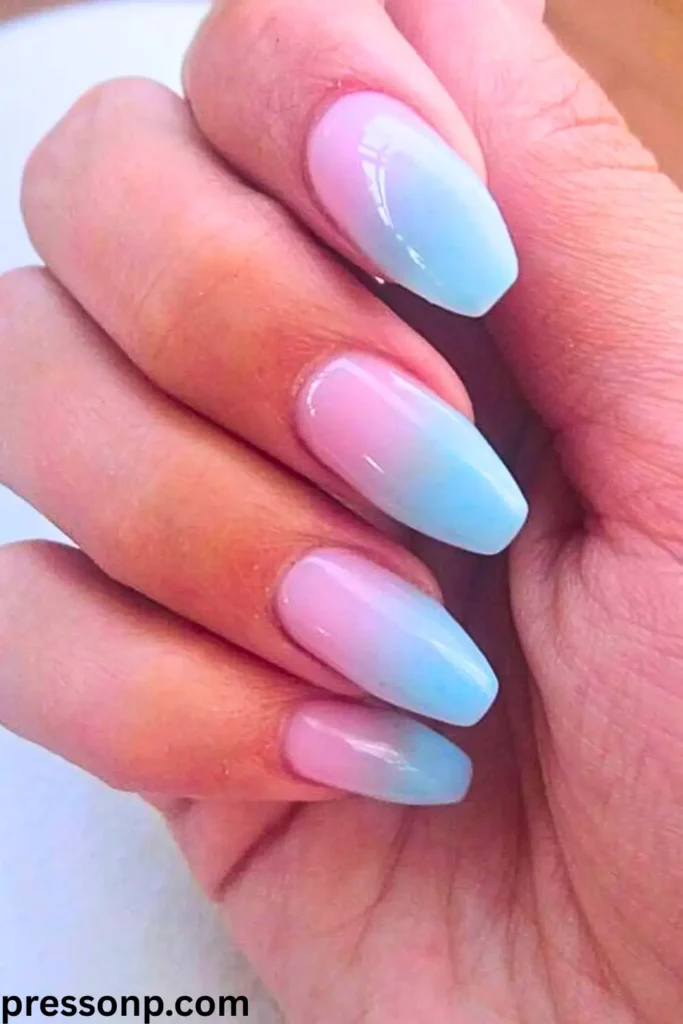 A close-up of a hand with long, square-tapered nails featuring a smooth cotton candy ombré effect that seamlessly blends soft pastel pink at the base into a light baby blue at the tips.