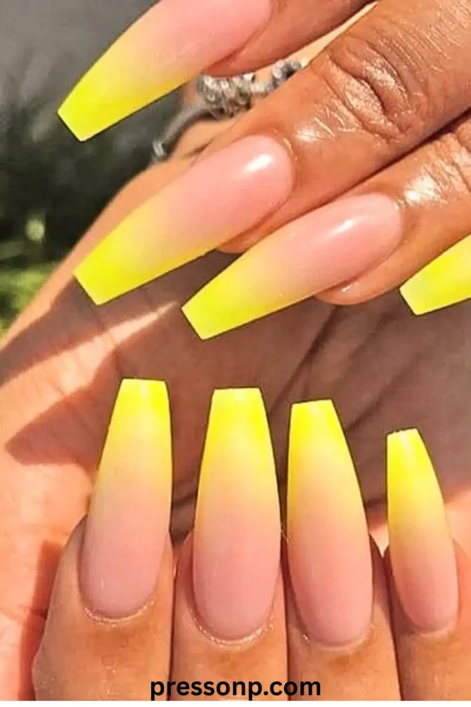 A close-up of long coffin-shaped nails featuring a smooth ombré gradient that fades from a soft nude base to a vibrant electric yellow at the tips.