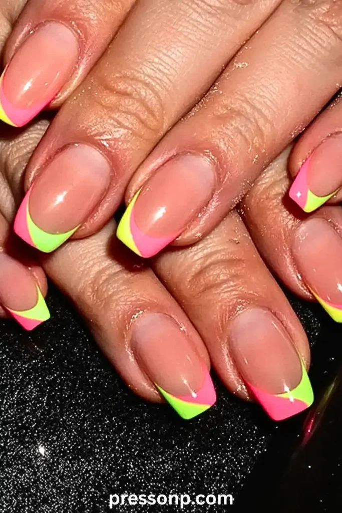 A close-up of square-shaped nails featuring a natural base and a two-toned neon French tip in vibrant pink and lime green, set against a shimmering black background.