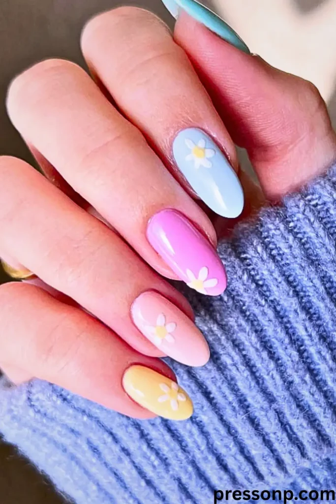 "Natural-length almond nails featuring a vibrant pastel skittles manicure in sky blue, orchid purple, soft peach, and sunny yellow. Each nail is decorated with a delicate white daisy accent and finished with a thick, protective high-gloss top coat to ensure longevity. The pressonp.com watermark is visible in the bottom right corner."