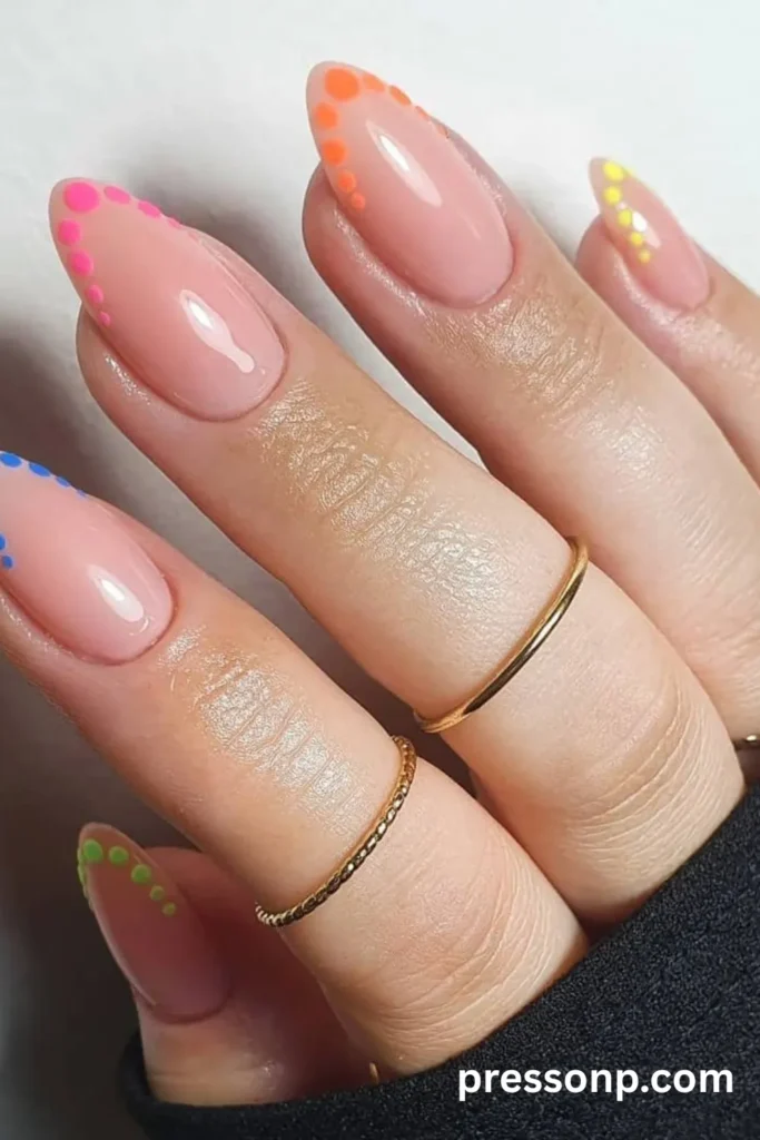 Sheer pink almond nails with a minimalist rainbow dot border tracing the outer edges.