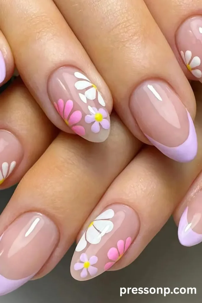 Close-up of long almond acrylic nails with a glossy clear base, featuring pastel lavender French tips paired with retro white, pink, and purple daisy accent nails.