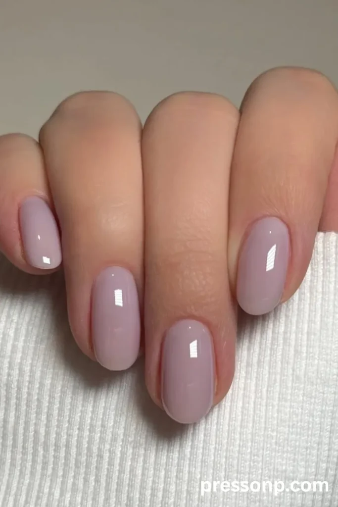 Close-up of medium-length oval nails with a glossy, solid pale lavender cream gel manicure