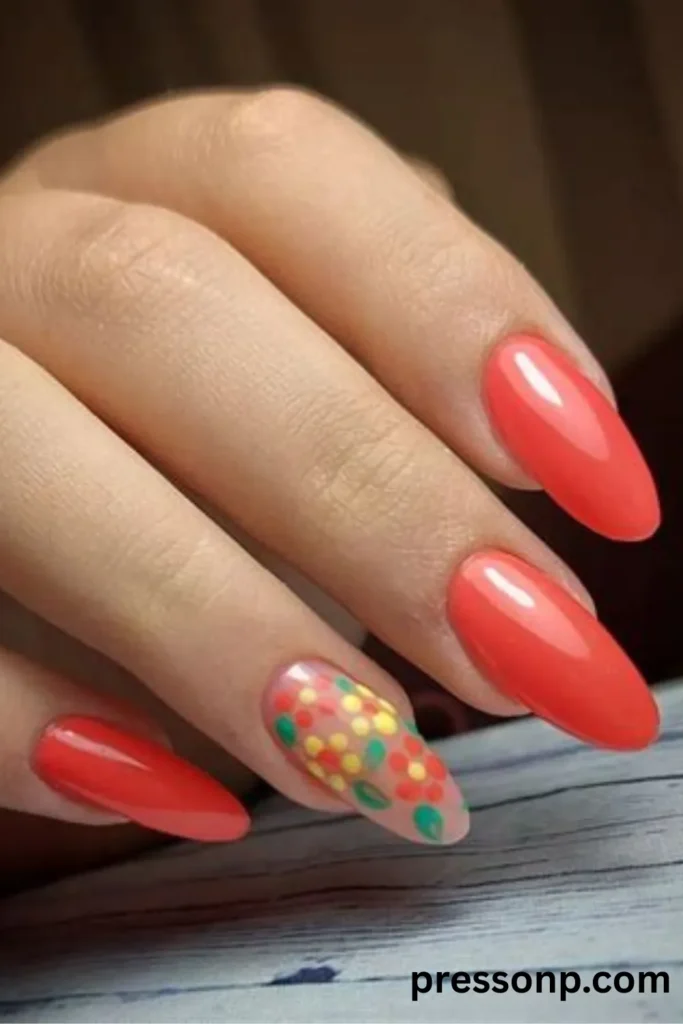 Close-up of long almond-shaped nails featuring a solid, glossy electric coral pink polish paired with a clear accent nail decorated with colorful retro floral patterns.