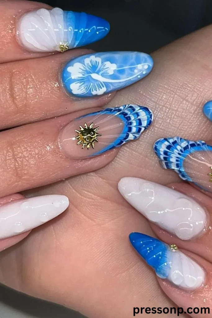 A close-up of long, almond-shaped extension nails displaying an intricate, multi-textured 3D ocean manicure in vibrant shades of electric blue, royal blue, and milky white, complete with hand-painted hibiscus flowers and metallic sun charms.