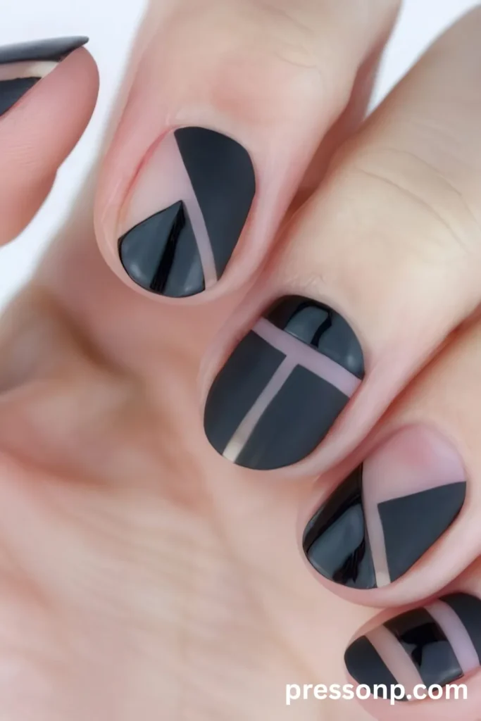 Close-up of short, round manicured nails featuring an edgy, minimalist black geometric design with contrasting matte and glossy finishes separated by bare negative space cutouts.