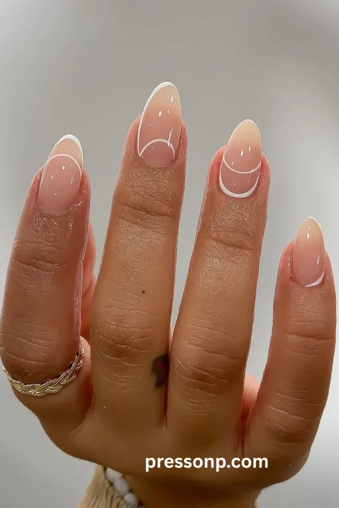 A close-up photograph of a hand displaying a minimalist negative-space manicure on long almond nails, featuring a sheer, high-gloss nude base decorated with clean, delicate white line work mimicking abstract French tips and geometric half-moons.