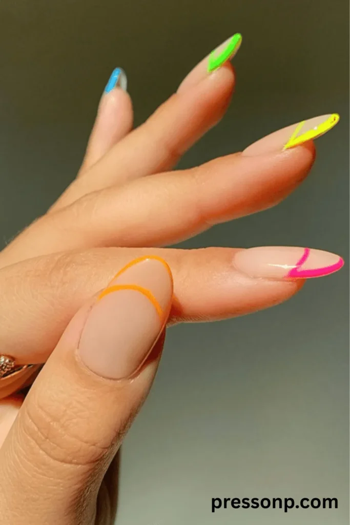 A close-up of a hand displaying a modern, multi-colored neon French tip manicure on long oval nails, featuring a sheer nude base decorated with vibrant, abstract minimalist linework tips in bright orange, electric pink, neon yellow, lime green, and sky blue.