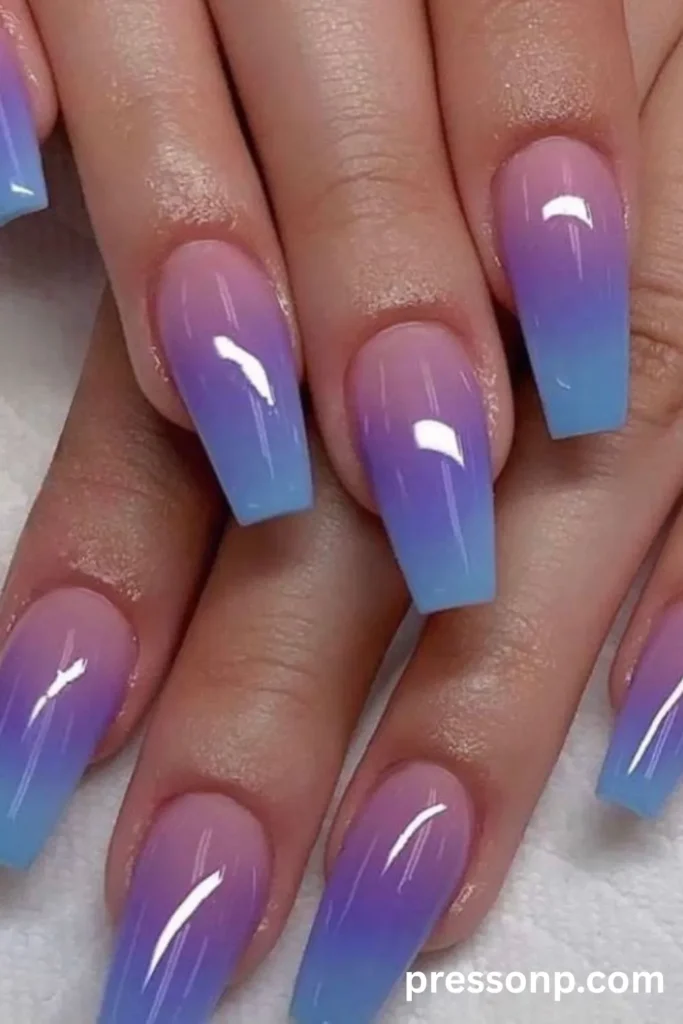 Close-up of long coffin-shaped acrylic nails featuring a vibrant, high-gloss neon ombré gradient that smoothly transitions from soft pink to purple and electric blue.