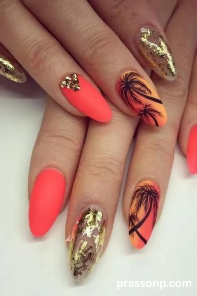 Close-up of long almond acrylic nails featuring a vibrant summer design with matte neon coral polish, textured gold foil accents, and hand-painted black palm tree silhouettes over a sunset ombré gradient.