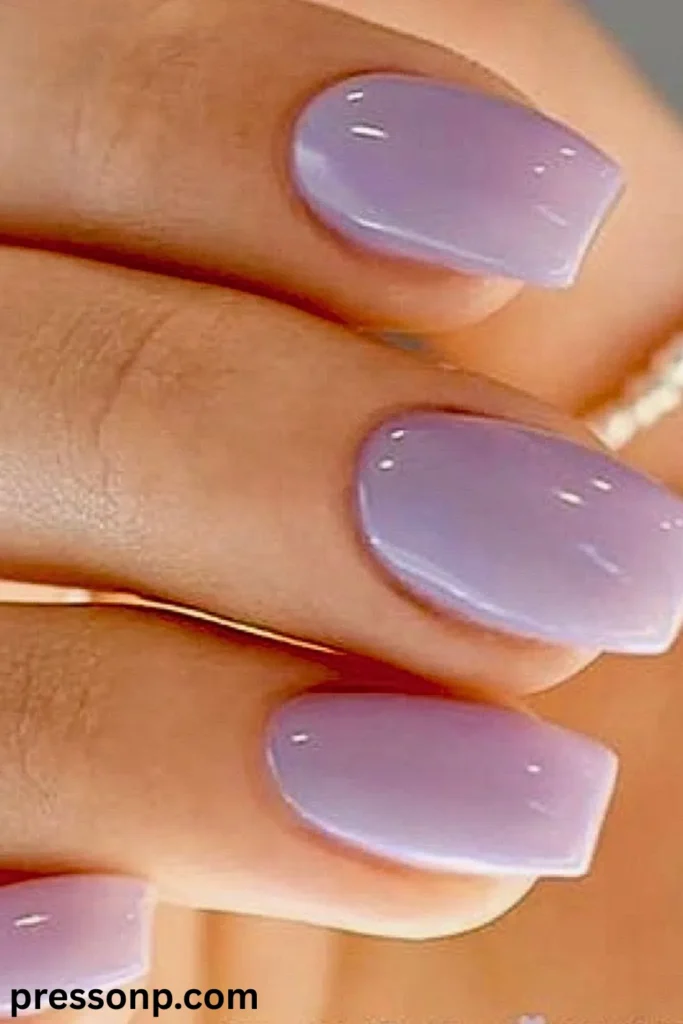 A close-up of a hand showcasing short, natural square-oval nails with a high-gloss, semi-translucent pastel lavender purple jelly manicure.