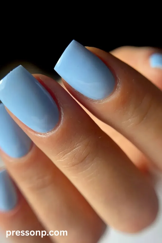 Close-up of medium square nails painted in a solid, high-gloss sky blue polish