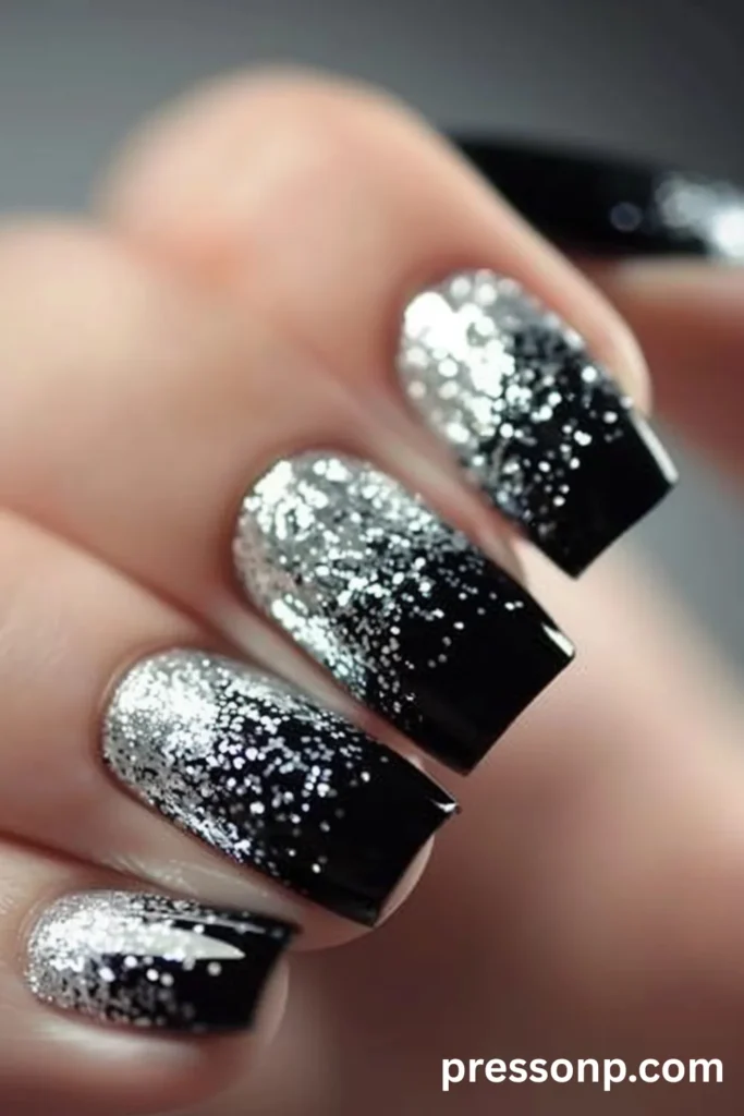 Close-up of medium square acrylic nails with a glossy black base, featuring a heavy silver glitter gradient cascading down from the cuticles