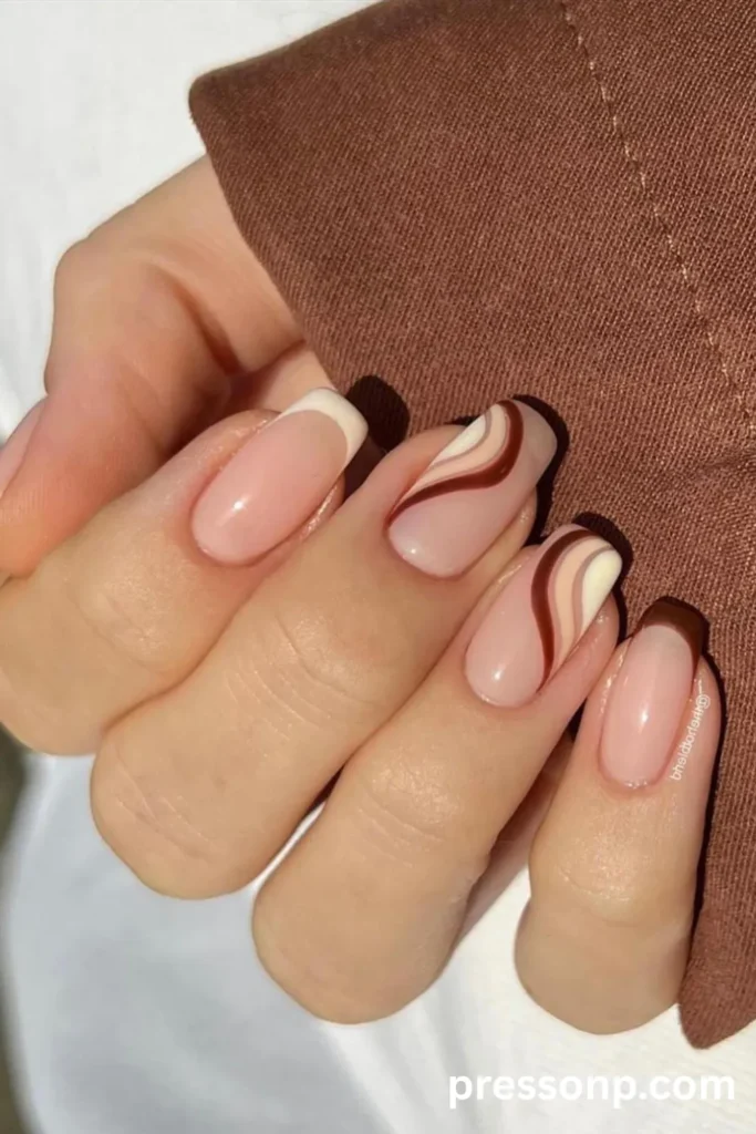 Close-up of medium-length oval nails with a sheer nude base, featuring vanilla white and chocolate brown French tips mixed with wavy, abstract squiggly lines in melted ice cream colors