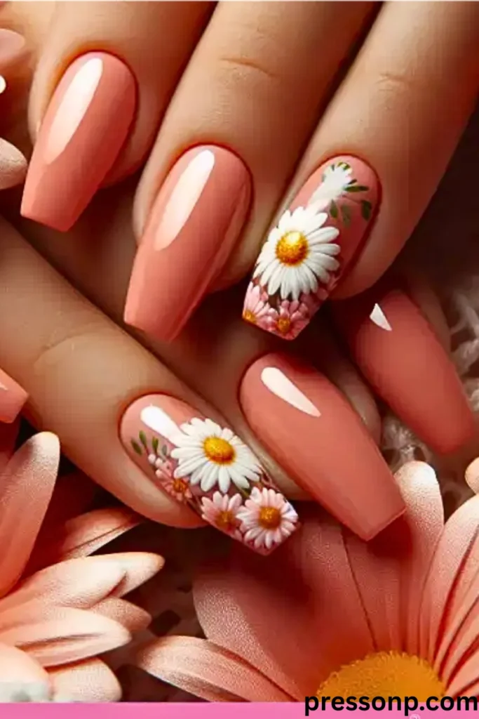 A close-up of hands displaying a high-gloss summer manicure on long, coffin-shaped extensions in a creamy watermelon-pink shade, featuring accent nails beautifully adorned with detailed white and pink daisy illustrations