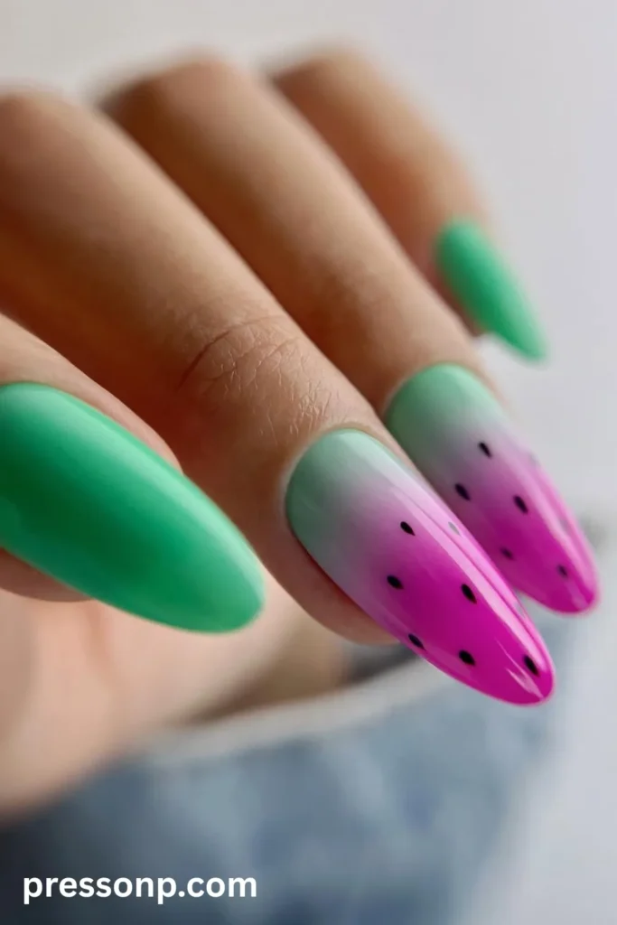 Close-up of long almond-shaped nails featuring a mix of solid vibrant mint green polish and a smooth pink-to-green ombré watermelon gradient complete with black seed accents