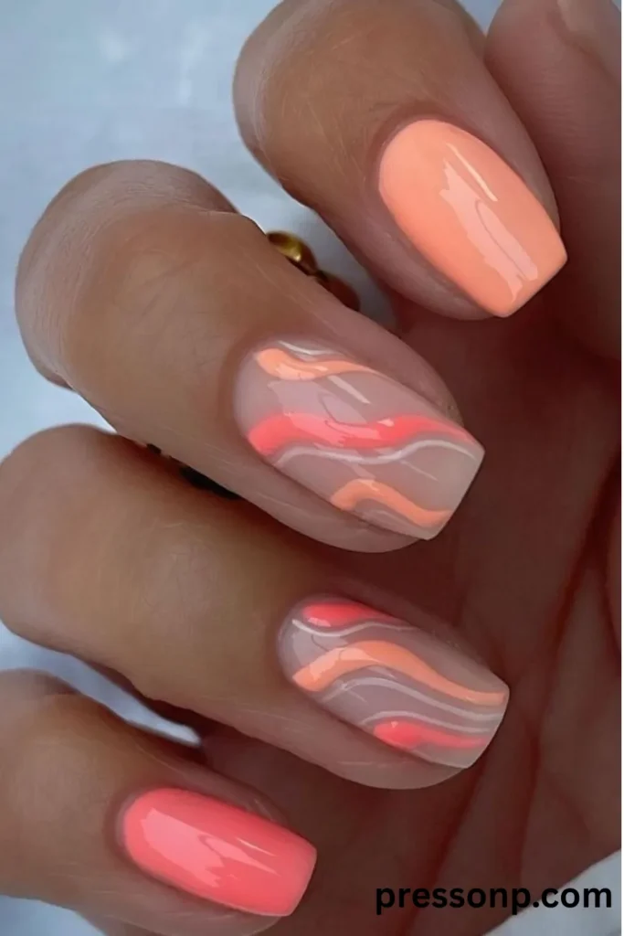 Close-up of a hand with square-shaped nails featuring a mix of solid peach and coral pink gel polish alongside clear accent nails detailed with abstract wavy swirls.
